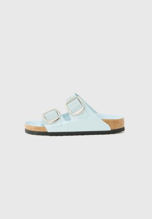 Light blue sandals with two adjustable silver buckles, cork sole, textured footbed, and a black rubber outsole.