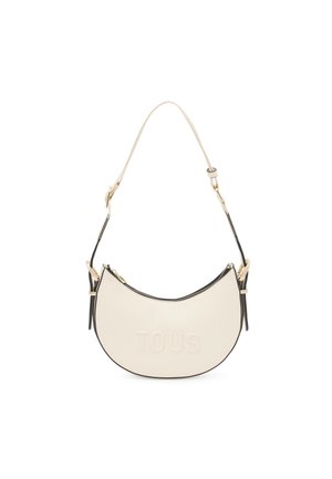 Borsa in pelle color crema con forma curva, dettagli neri, hardware dorato e logo "TOUS" impresso sul davanti. Tracolla regolabile.