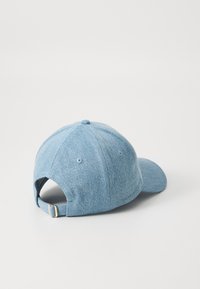 Cappellino da baseball in denim azzurro chiaro con corona arrotondata, cinturino regolabile sul retro e fori per la ventilazione. Superficie del tessuto testurizzata.