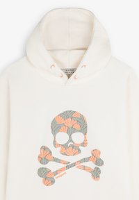 Crème hoodie met een bloemige doodskop en gekruiste botten ontwerp in grijs en perzik. Inclusief oranje eyelet-accenten op de capuchon.