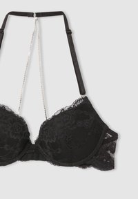 Reggiseno in pizzo nero con coppe imbottite, motivo floreale e spalline regolabili. Presenta dettagli in catena e chiusura a gancio e occhiello sul retro.