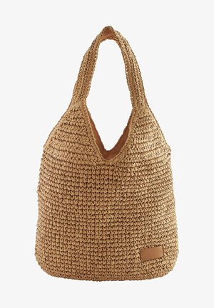 Sac en paille tissée avec une forme décontractée, de couleur sable, ouverture en V et étiquette en cuir en bas. Texture douce.