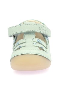 Zapato de cuero verde con diseño de cortes, correa ajustable y suela suave color beige. Forrado con un interior de patrón floral.