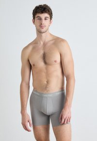 Grå Calvin Klein boxertruser laget av elastisk stoff, med en logo-belte og en tettsittende design for komfort.