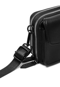 Černá kožená křížová taška s dvojitými zipy, texturovaným povrchem, nastavitelním popruhem a přední kapsou s klopou.