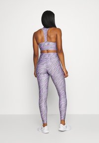 Purple and gray athletic set featuring a racerback sports bra and high-waisted leggings with a tiger stripe pattern. Smooth, stretchy fabric.