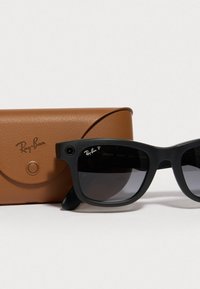 Ray-Ban sunglasses with black plastic frame and dark lenses, alongside a brown leather case featuring a button closure and raised logo.