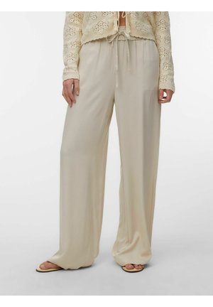 Pantalon beige à jambes larges avec taille à cordon, porté avec des sandales à bouts ouverts et un haut long en crochet crème.
