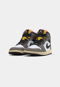 Par de tênis Nike Air Jordan de cano alto em cinza, branco, preto, amarelo e rosa, com cadarços pretos, exibidos lado a lado sobre um fundo branco.