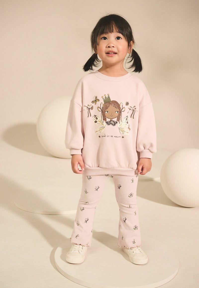 Roze sweatshirt met een grafisch ontwerp van een meisje en bloemenaccenten, gecombineerd met geribde roze broek met een bloemenpatroon en rafelige zomen.