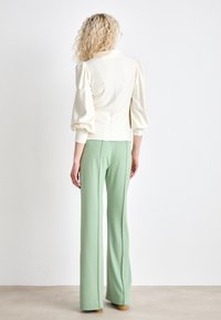 Cream puff-sleeve top paired with light green flared trousers, featuring a smooth texture. Minimalistic design without additional embellishments.