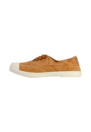 Zapatilla de lona color beige con una puntera blanca de goma, cordones redondos y superficie texturizada. Suela plana con un patrón de agarre texturizado.