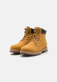 Botas de cuero marrón con acentos negros, diseño con cordones, cuellos acolchados y suelas de goma texturizadas. Presentan ojales de metal y detalles cosidos.