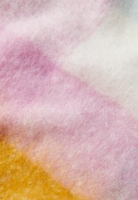 Villane kangas, millel on gradient disain roosa, valge ja kollase tooni kombinatsioon, pehme tekstuur ja veidi karvane pind.