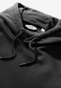 Black hoodie with a soft texture, featuring a drawstring hood, and a label reading "NEXT" inside the neckline.