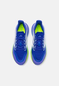 Chaussures de sport bleues avec des rayures blanches, tige en maille, boîte à orteils texturée, et accents vert néon sur la semelle et la semelle intérieure. Lacets inclus.
