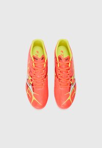 Scarpe da calcio arancione brillante con accenti neri e gialli, materiale sintetico liscio e design con lacci. Fodera interna giallo neon.