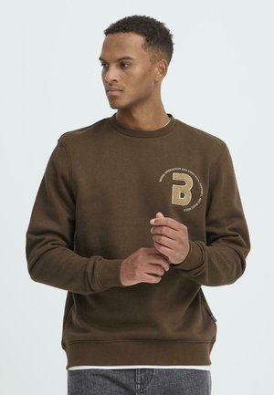 Bruine sweatshirt gemaakt van gestructureerde stof, met een ronde halslijn en een opvallend logo-detail op de linkerkant van de borst. Verstelbare manchetten.