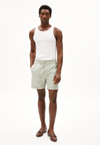 Lichtgroene shorts met een elastische tailleband en een trekkoord, gecombineerd met een witte tanktop en bruine leren instappers. Eenvoudig ontwerp, comfortabele pasvorm.