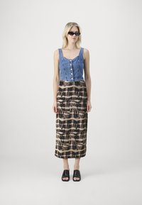 Džínový crop top s detailmi na gombíky, skombinovaný s patterned dlhou sukňou v čiernej, krémovej a hnedej farbe. Celý outfit dopĺňajú čierne slide sandále.