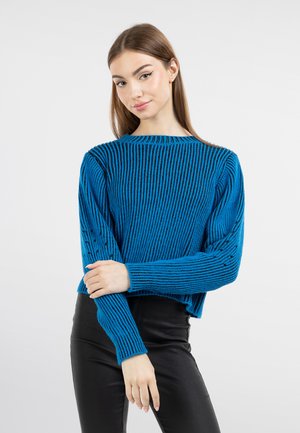 Pulover tricotat albastru, cu maneci lungi și decolteu rotund, având un design scurt și un model texturat. Asortat cu pantaloni negri.