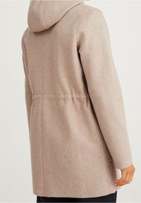 Abrigo de lana beige claro con capucha, cintura ajustada y textura suave. Presenta un acabado liso y detalles de costura sutiles en la parte posterior.