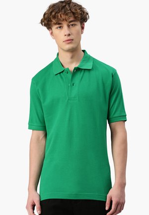 Polo verde realizzata in cotone, con colletto, maniche corte e orlo dritto. Include una chiusura a tre bottoni.