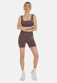 Braunes, geripptes Sportset mit einem Top mit quadratischem Ausschnitt und hochgeschnittenen Shorts, das mit einem weißen Logoakzent und einer glatten Textur versehen ist.