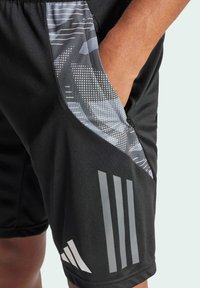 Schwarze Sportshorts mit einem grauen gemusterten Einsatz, Seitentaschen und drei vertikalen Streifen am Unterschenkel. Glatte Stoffstruktur.