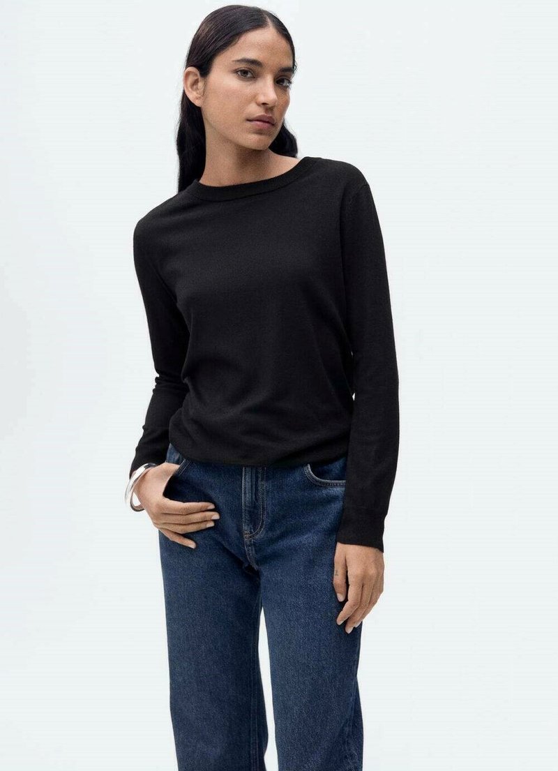 Black long-sleeve top made of a smooth fabric, paired with blue high-waisted jeans. The top features a wide neckline and relaxed fit.