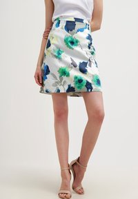 Květinová sukně z lehké látky s modrými, zelenými a šedými abstraktními vzory. Délka nad kolena, s přiléhavým pasem a mírným rozšířením.