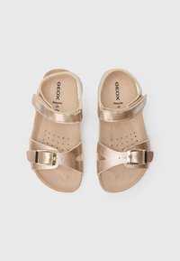 Arany színű fémes gyermek szandál állítható csattal és pánttal, lyukacsos talpbetéttel és világos barna talppal. Méret: 28.