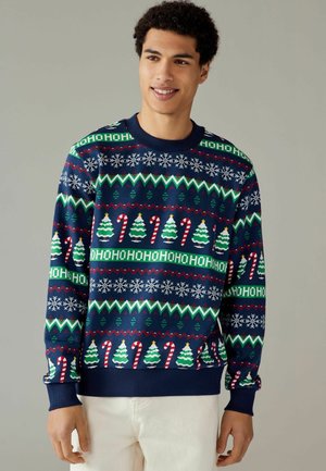 Dunkelblauer Pullover mit Weihnachtsmustern, der Bäume, Zuckerstangen und Schneeflocken in Grün, Rot und Weiß zeigt. Weiches Strickgewebe.