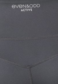 Sorte træningstights i aktivt tøj med glat, strækbart stof, syningsdetaljer og 'even&odd ACTIVE' logo i hvid.
