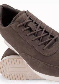 Bruna mockaskor med en slät yta, rund tå, platta snören och en vit gummisula med ett mönster.