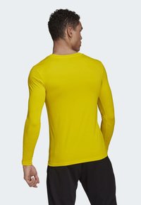 Geel sportshirt met lange mouwen in een soepele, aansluitende pasvorm, met een ronde halslijn en mouwen tot aan de pols.