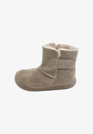 Botín de ante beige con forro de piel sintética suave, suela plana y detalle de correa diagonal con acentos de costura.