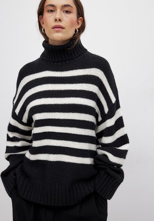 Black and white striped turtleneck sweater with a loose fit, ribbed cuffs, and hem. Soft knit texture, featuring wide horizontal stripes.