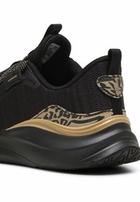 Czarne buty sportowe z teksturowanej tkaniny, złotymi akcentami i wzorem w panterkę na pięcie. Posiadają grubą czarną podeszwę i pętelkę do zakładania.
