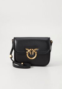 Μαύρο δερμάτινο τσαντάκι χιαστί με μαγνητικό καπάκι, εξαρτήματα σε χρυσό τόνο και διακοσμητικό έμβλημα χελιδονιού στο μπροστινό μέρος, με αποσπώμενο ιμάντα.