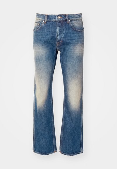 Ανοιχτό μπλε τζιν παντελόνι καμπάνα με φθορές στους μηρούς, πέντε τσέπες, μεταλλικό κούμπωμα και αντίθετες ραφές.