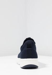 Granatowe siateczkowe sneakersy z teksturowanej tkaniny, z pętelką na pięcie i białą gumową podeszwą o niskim profilu.