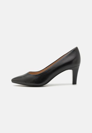Sorte skinn pumps med høy hæl, spiss tå, slankt design, moderat hæl og glatt tekstur. Interiøret har en brun fôr.