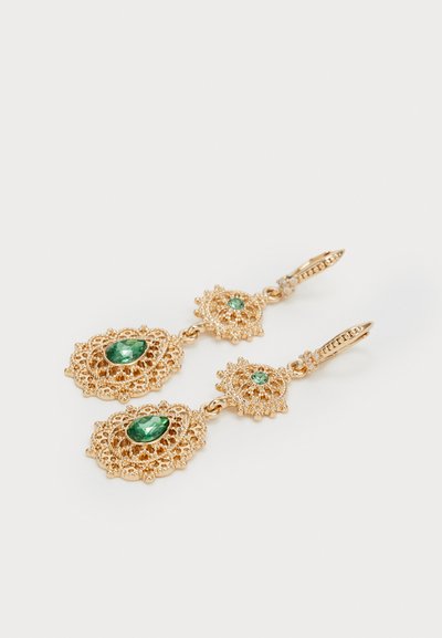 Pendientes colgantes en tono dorado con un intrincado diseño similar al encaje, que presentan dos piedras preciosas verdes y acentos más pequeños sobre un respaldo decorativo.