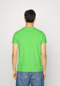 Vihreä lyhythihainen T-paita, joka on valmistettu puuvillasta, ja siinä on pyöreä pääntie sekä rento malli. Tasainen pinta ilman kuvioita ja yksivärinen.