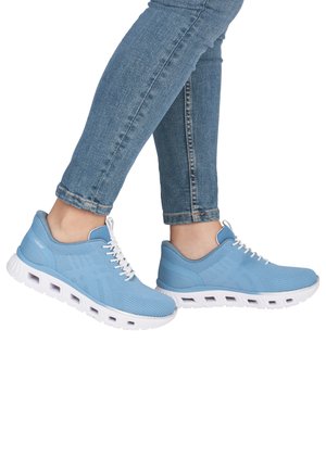 Feet wearing light blue athletic shoes with white soles and laces, paired with cuffed blue denim jeans, shown from the side on white background.