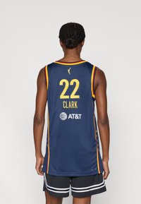 Μπλε μπασκετική φανέλα με ζωντανές κίτρινες και κόκκινες λεπτομέρειες· διαθέτει τον αριθμό "22", το όνομα "CLARK" και το λογότυπο της AT&T. Υφασμα δίχτυ, χωρίς μανίκια.