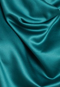 Tejido de satén color teal con una textura suave y brillante, que presenta pliegues suaves y ondulantes que crean profundidad y dimensión.