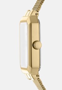 Orologio in metallo dorato con cassa rettangolare, quadrante in vetro trasparente e cinturino a rete texturizzato. Include una corona rotonda sul lato.
