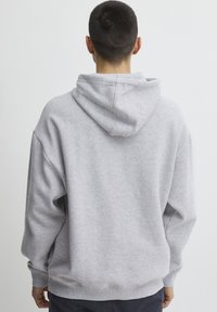 Gray cotton hoodie with a relaxed fit, featuring a drawstring hood and ribbed cuffs. Smooth texture and no visible graphics or patterns.